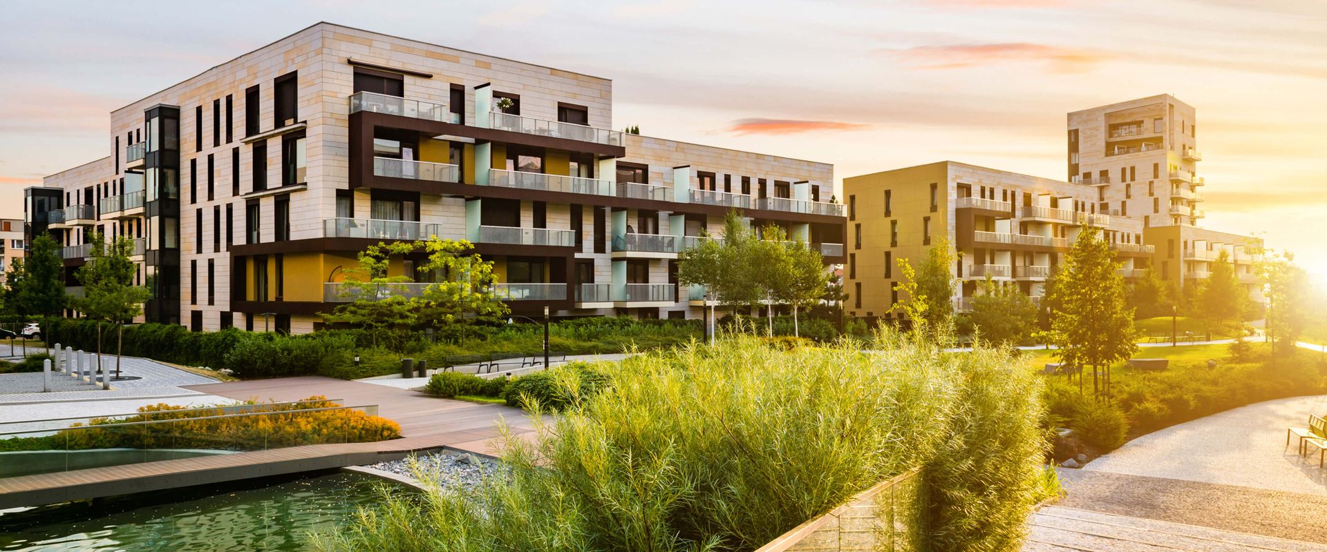 Moderne Wohngebäude in einer Stadt während des Sonnenuntergangs, die warmes Licht und eine einladende Atmosphäre ausstrahlen.